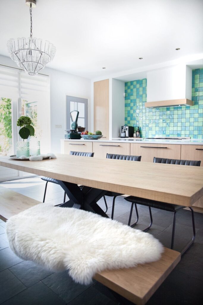 Keuken met groen en blauwe gekleurde tegels, eetkamertafel met drie stoelen en een bankje.