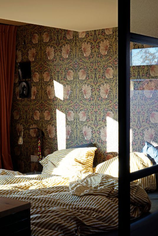 Masterbedroom met decoratief bloemenprint behang. Geel met wit gestreept dekbedovertrek.