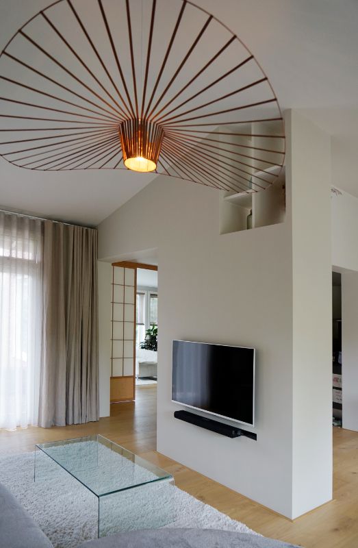 Roomdivider met televisie. Koperen hanglamp.