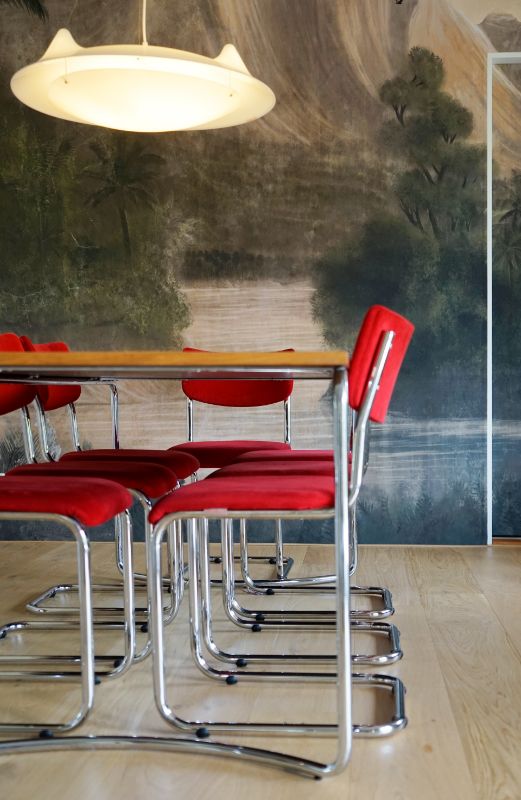 Eetkamer met rode stoelen en decoratief behang.