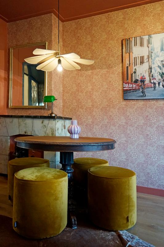 Kleurrijke kamer met klassieke ronde tafel en vier gele poefen.