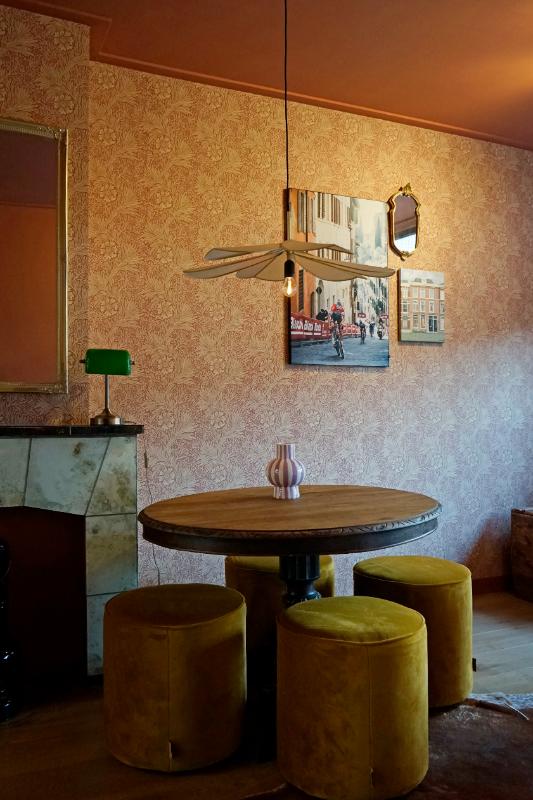 Kleurrijke kamer met klassieke ronde tafel en vier gele poefen.