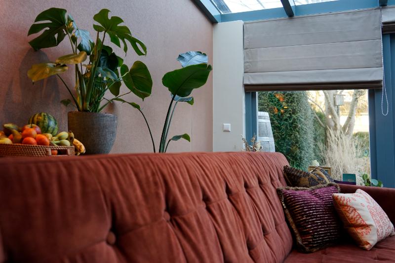 Blauw geschilderde kozijnen. Rode bank met LOVI kussens.