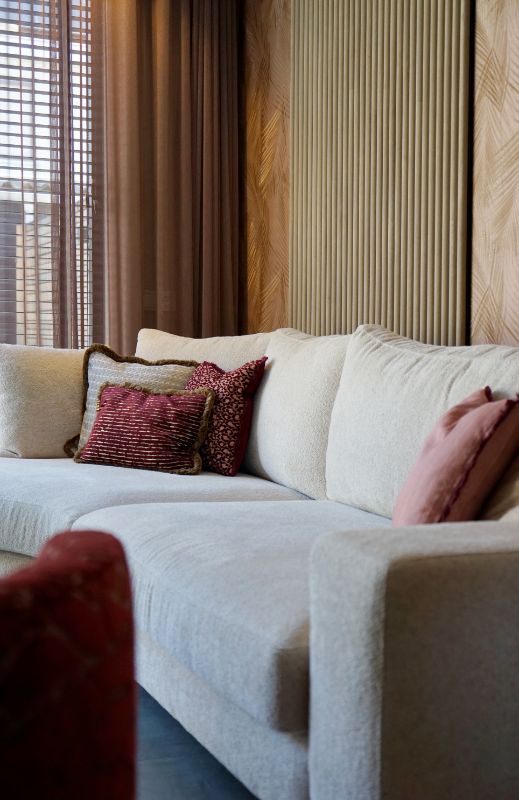 LOVI kussens op de lichte bank met druppel. Hierachter akoestische panelen. Roze inbetween gordijnen.