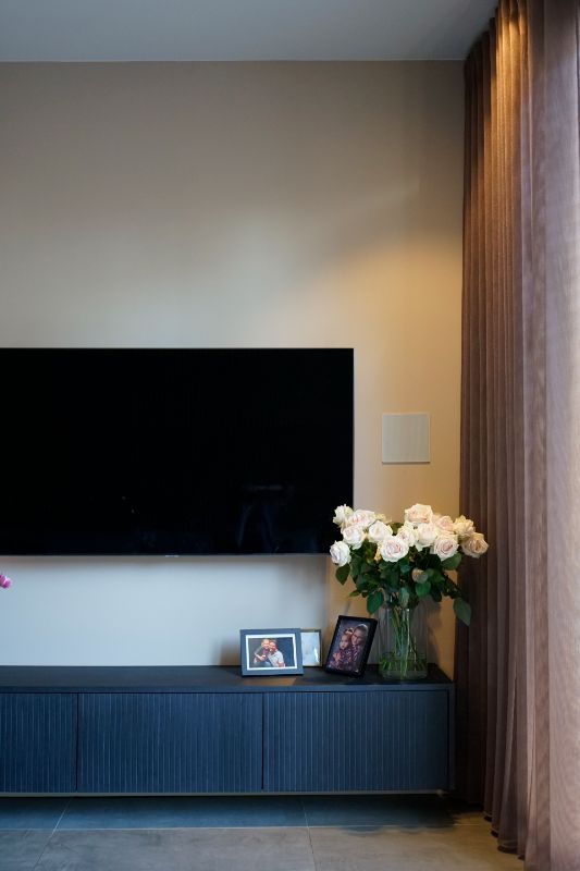 Zwevend tv meubel. Roze inbetween gordijnen.