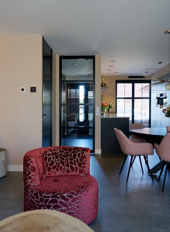 Rode fauteuil in een print stof. Zwarte stalen deuren.