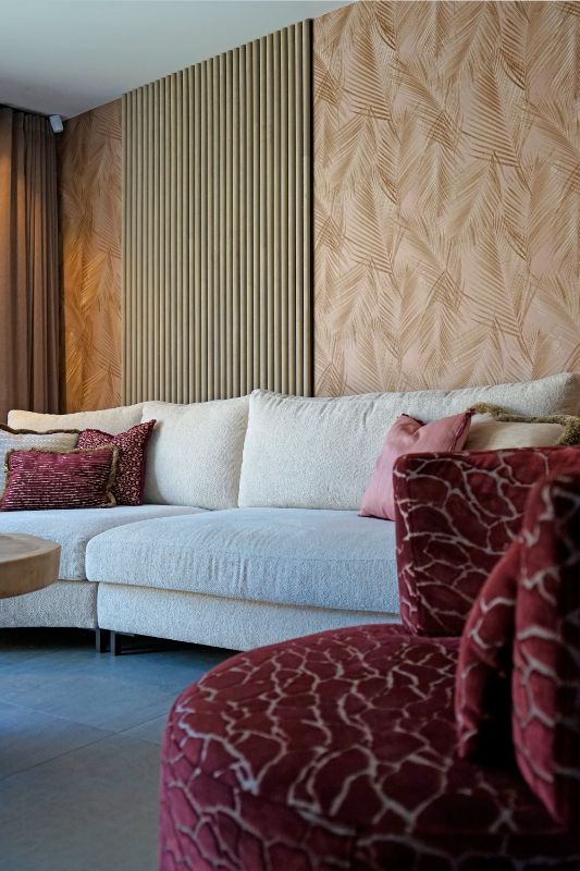 Lichte bank met bouclé stof. Mooie LOVI kussens. en akoestische panelen. En rode fauteuil met print.