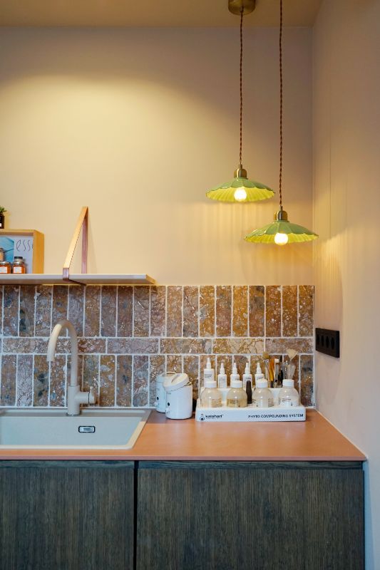 Keuken met gekleurde tegels. Groene hanglampen en beauty producten.