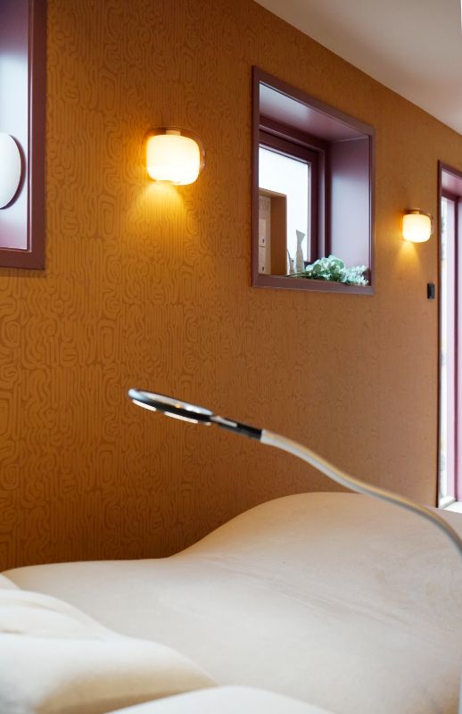 Ligstoel schoonheidssalon. Patroon behang op de wand, burgundy kozijnen.