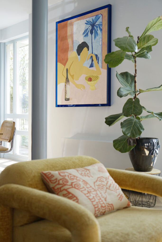 Detail gele fauteuil met LOVI kussen. Aan de wand een HKliving schilderij.