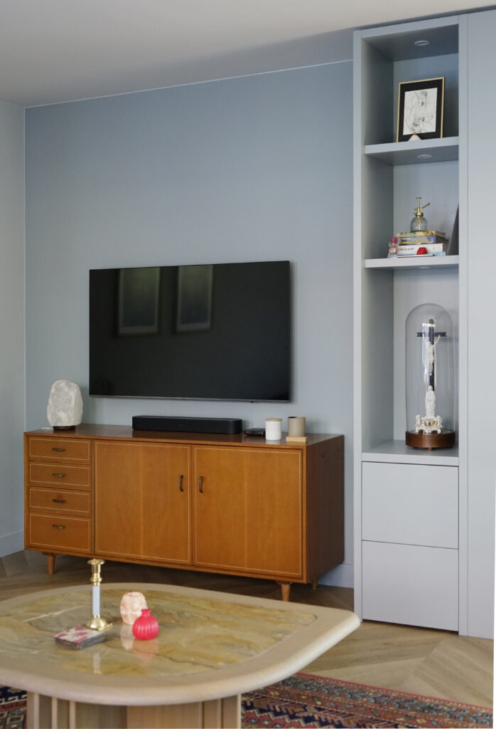 Lichtblauwe wanden met een lichtblauwe vakkenkast en een vintage tv meubel.