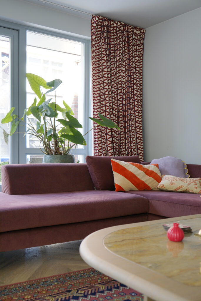 Woonkamer met modulaire roze bank en gekleurde kussens.