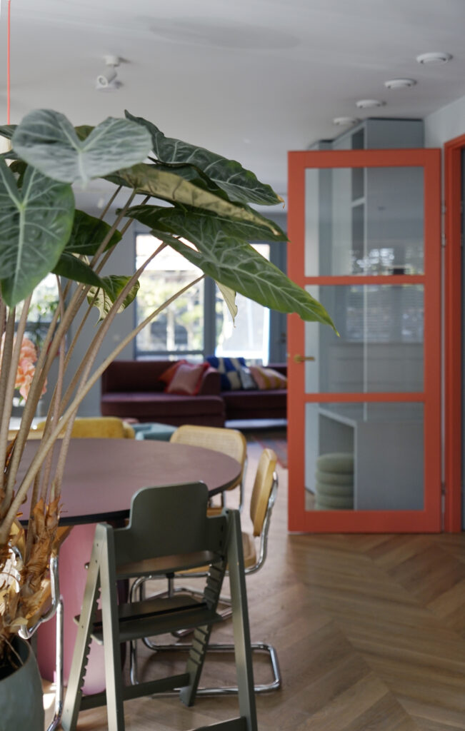 Oranje glazendeur. Bordeaux rode eettafel met rotan stoelen.