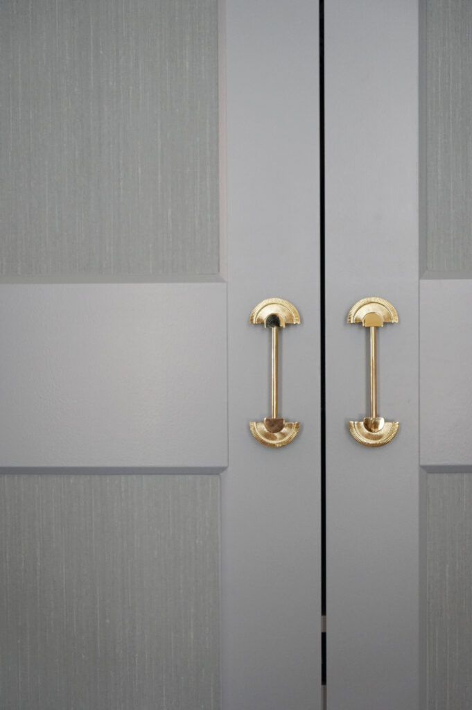 Licht blauwe kledingkast met gouden meubelgrepen.