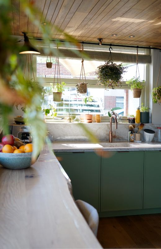 Groene maatwerk keuken met veel planten.