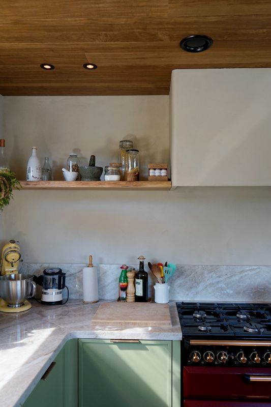 Groene maatwerk keuken met hout plafond. Mooie gestucte muren met wandplanken.
