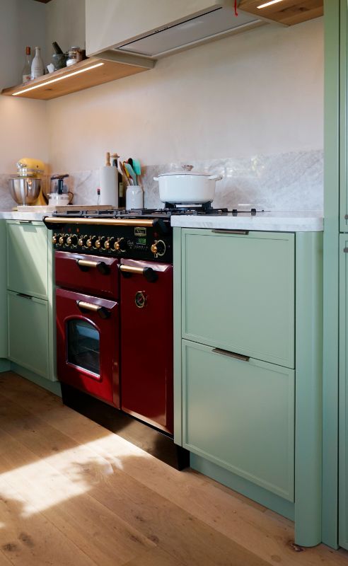 Groene maatwerk keuken met rood fornuis.