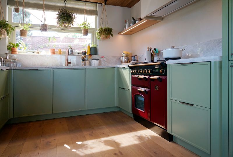 Groene maatwerk keuken met rood fornuis.