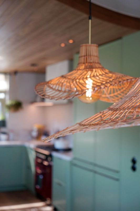 Groene maatwerk keuken met rieten hanglampen.