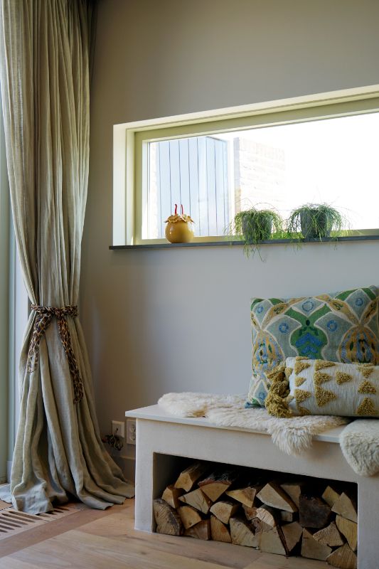 Leem kachel met een bankje en gekleurde kussens. Groene inbetween gordijnen.