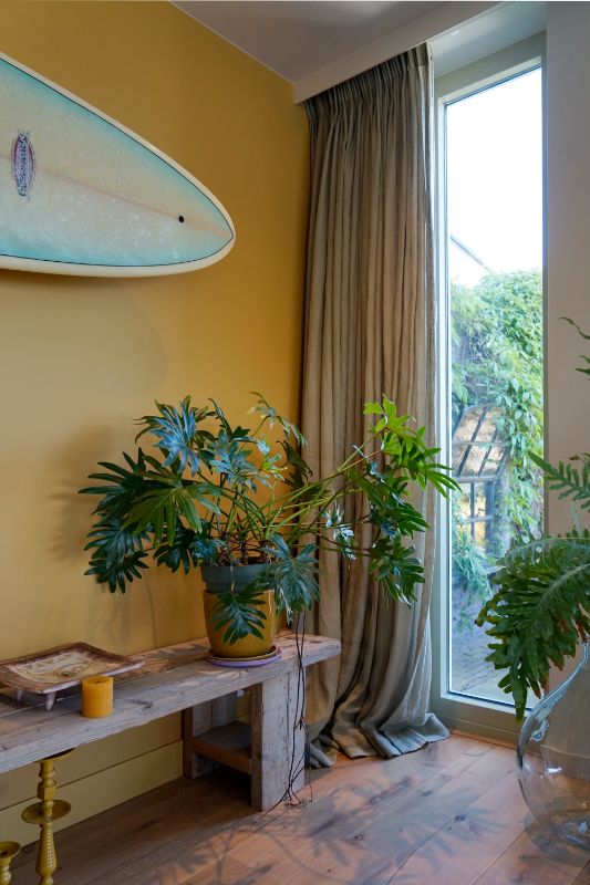 Geel geschilderde wand met een surfboard aan de wand.