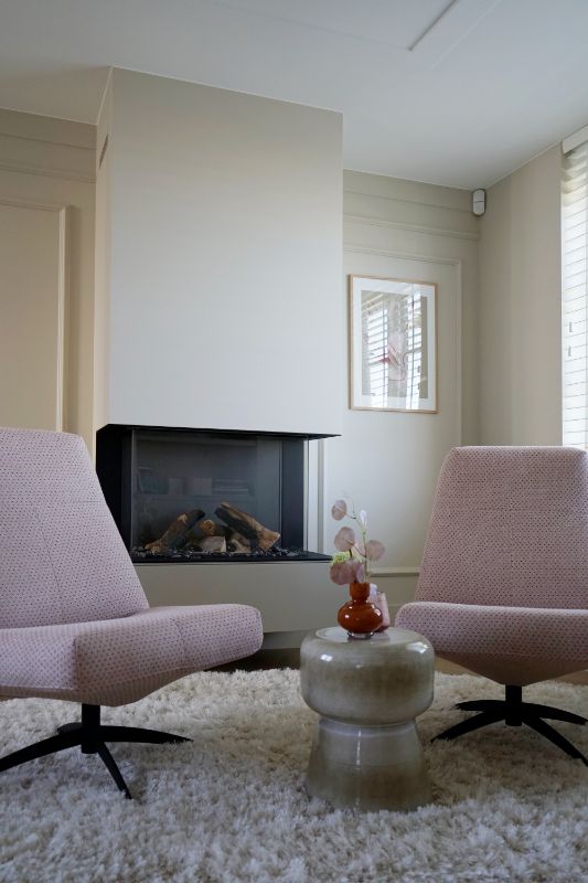 Roze fauteuils bij haard.