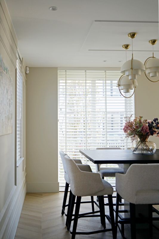 Lichte beige keuken met witte horizontale jaloezieën.