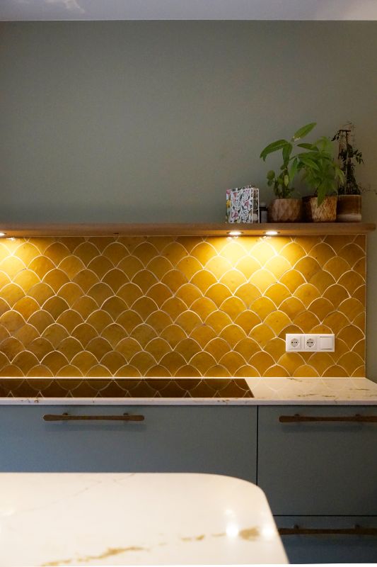 Groene keuken met een gele tegelwand in schelpmotief.