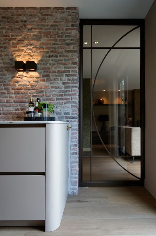 Seperatie van de keuken en de woonkamer door organische bronzen stalendeuren.