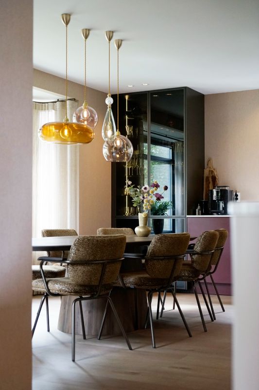 Rode keuken met servieskast. Eettafel met acht gele eetkamerstoelen.