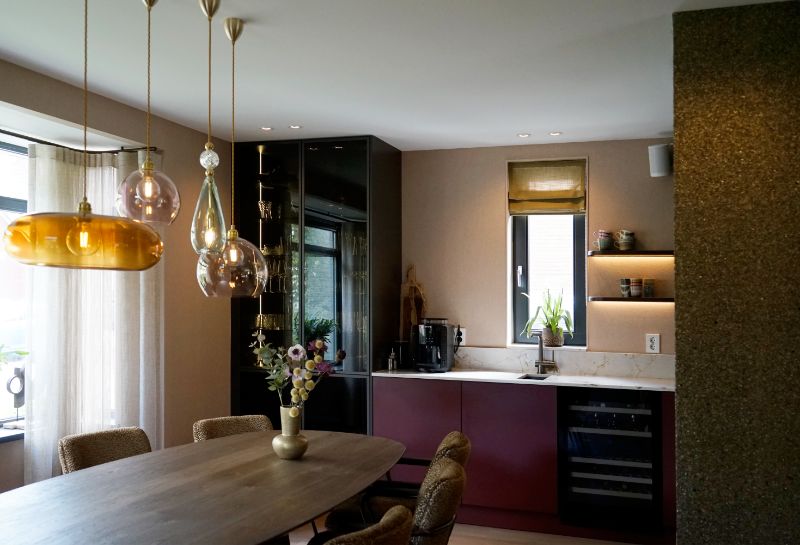 Gezellige warme eetkamer met een rode keuken, houten eettafel en gele eetkamerstoelen.
