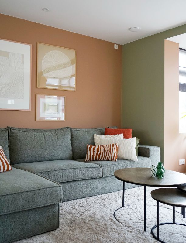 Woonkamer met terra en groen tinten. Op de grond een fluffy vloerkleed.